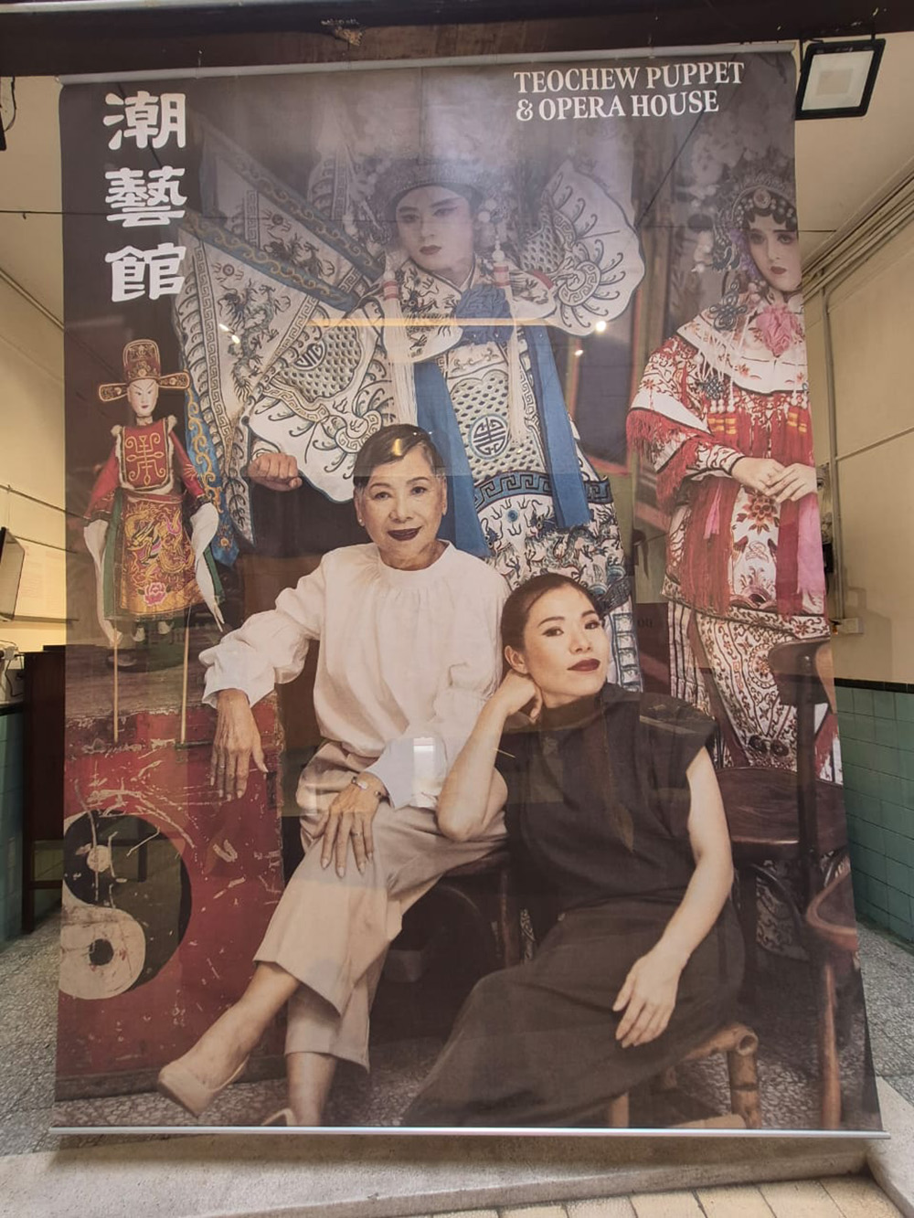 吳慧玲（右）與母親杜愛花的海報懸掛在潮藝館內，母女倆承先啟後，把檳城潮劇和潮州傳統鐵枝偶帶進現代劇場，找到新一代的年輕觀眾。